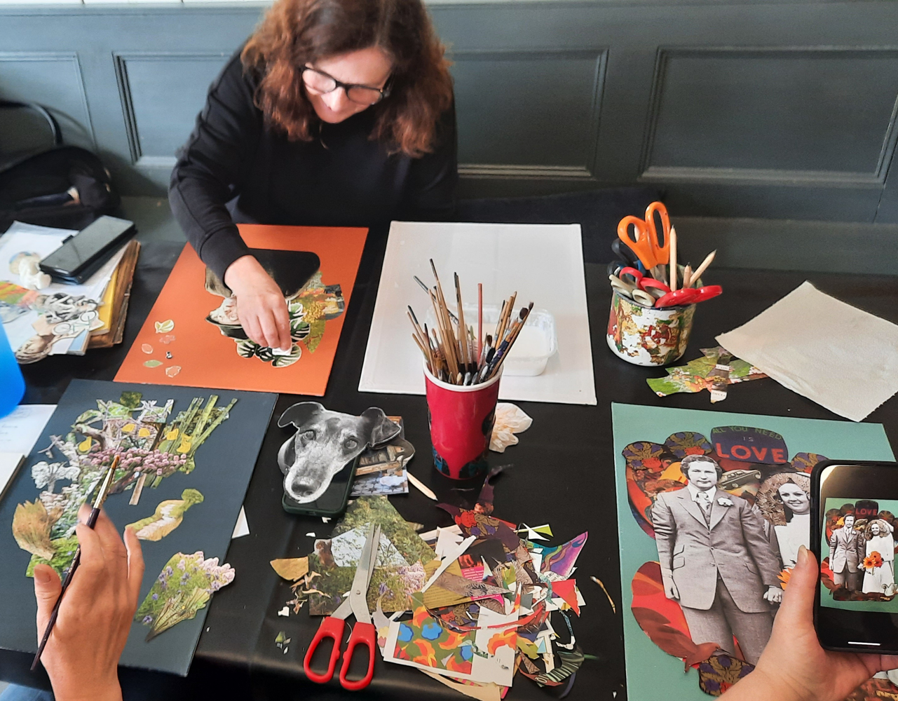 Person working on a collage at a table with various art supplies